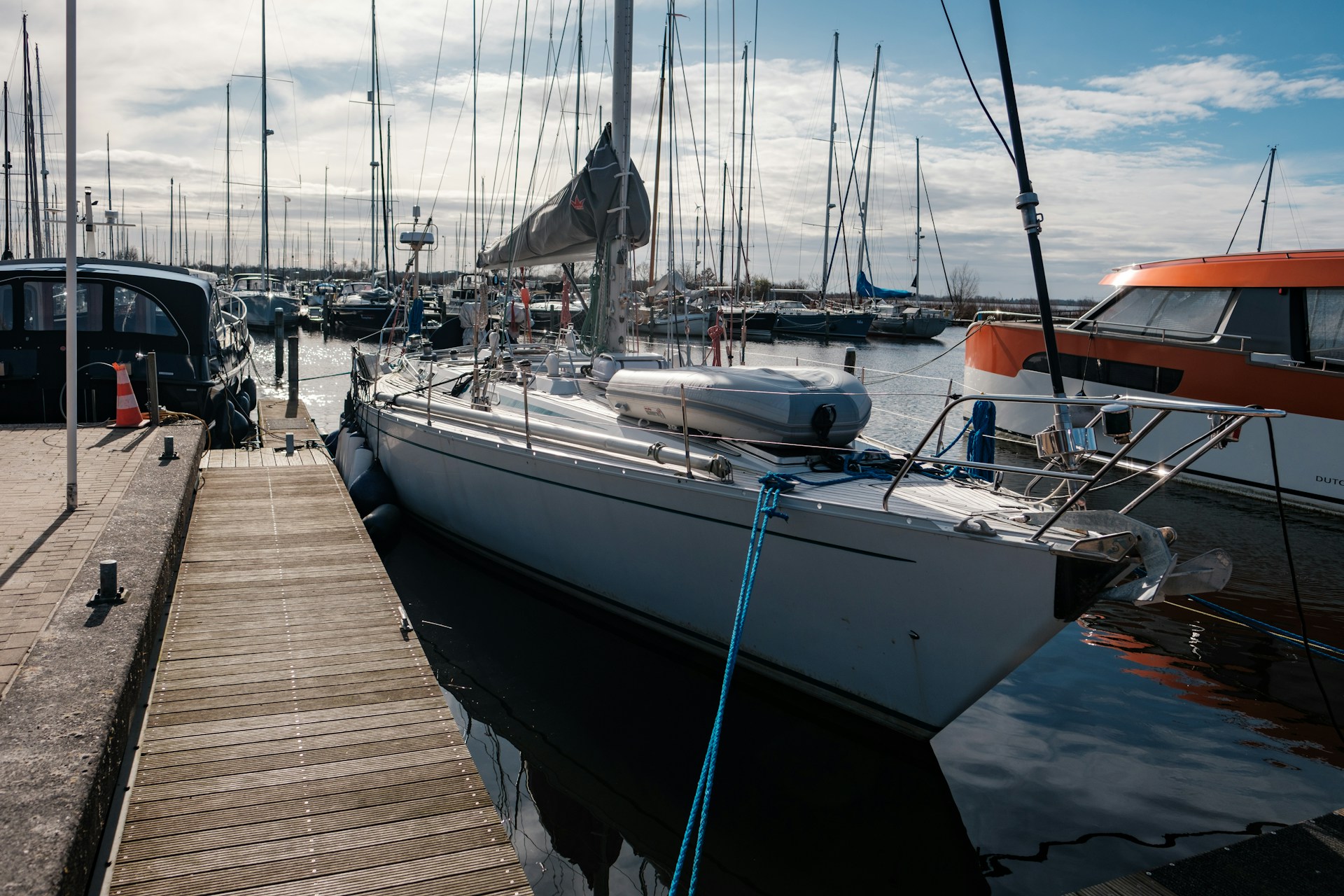 White monohull sailboat secured alongside a marina dock with fenders and dock lines.